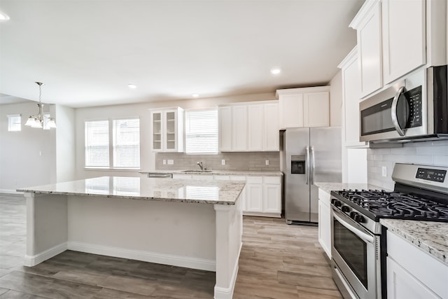 kitchen featuring white cabinets, stainless steel appliances, a center island, light hardwood / wood-style flooring, and sink