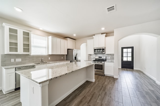 kitchen with white cabinets, appliances with stainless steel finishes, a kitchen island, and dark hardwood / wood-style flooring