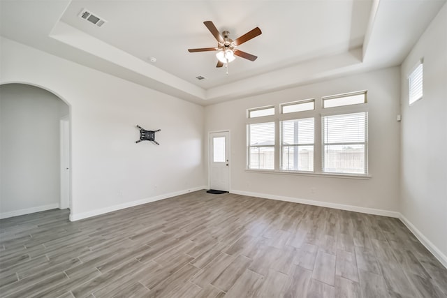 unfurnished room featuring light wood-type flooring, a tray ceiling, and ceiling fan