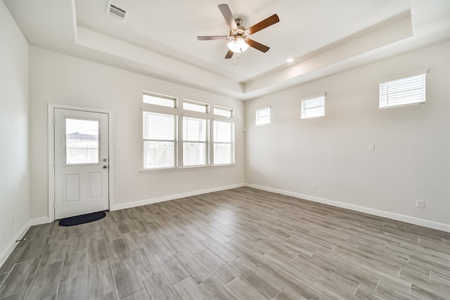 interior space with a tray ceiling, light hardwood / wood-style floors, and plenty of natural light