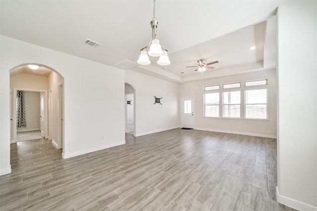 interior space featuring light wood-type flooring, ceiling fan, and a raised ceiling