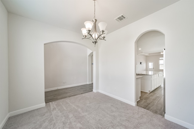 spare room featuring a notable chandelier and light colored carpet