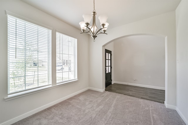 empty room with carpet floors and a notable chandelier