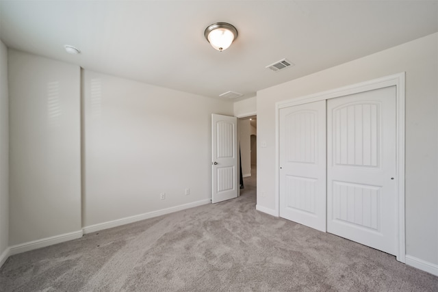 unfurnished bedroom with a closet and light colored carpet