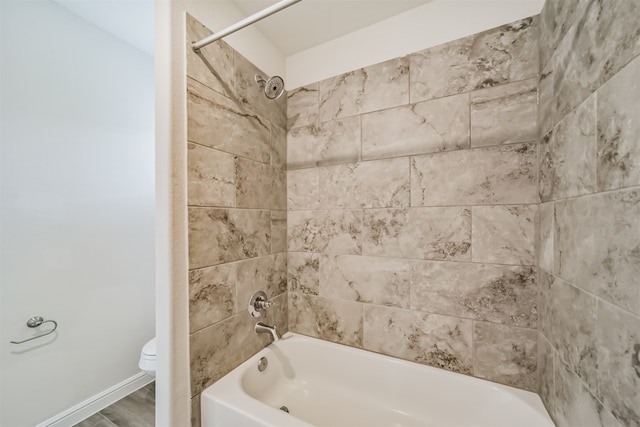 bathroom with tiled shower / bath, hardwood / wood-style flooring, and toilet