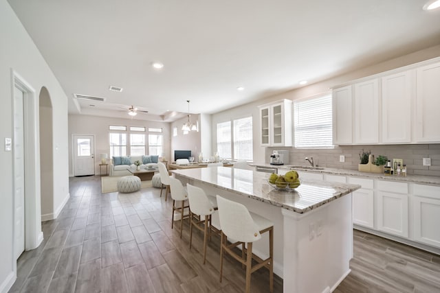 kitchen with white cabinets, backsplash, light hardwood / wood-style floors, and a kitchen island