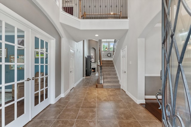 tiled entryway featuring a towering ceiling and french doors