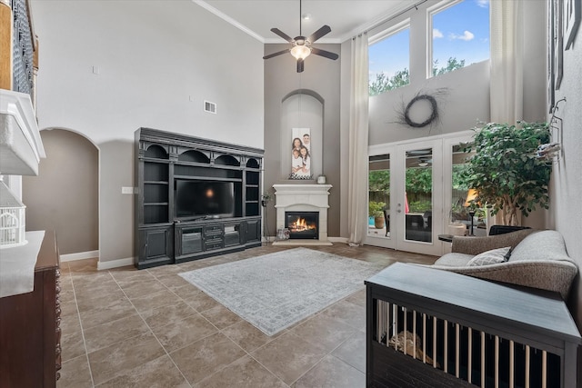 living room with a high ceiling, ornamental molding, and ceiling fan