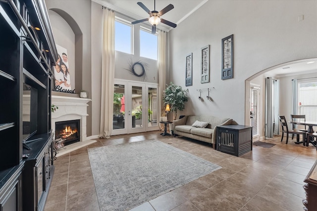 living room with ceiling fan, ornamental molding, plenty of natural light, and a high ceiling