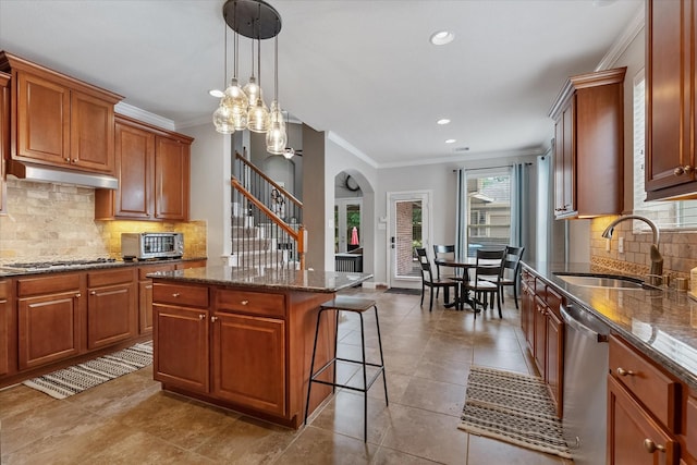 kitchen with appliances with stainless steel finishes, a kitchen island, a breakfast bar area, crown molding, and sink