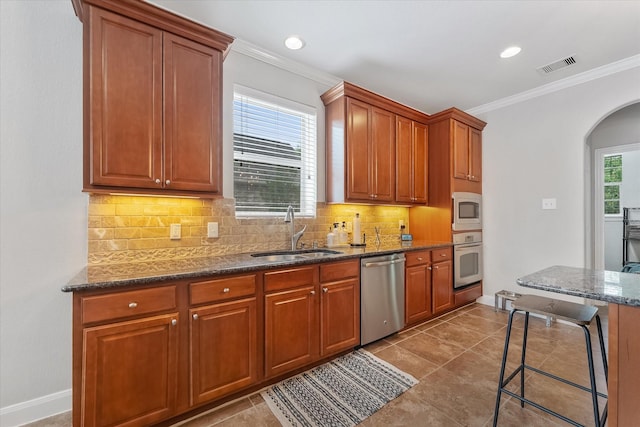 kitchen featuring decorative backsplash, stainless steel appliances, crown molding, and sink