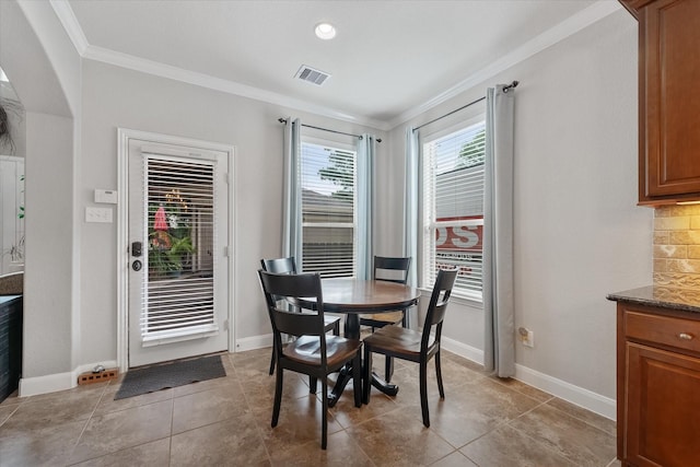 dining space with light tile patterned flooring and crown molding