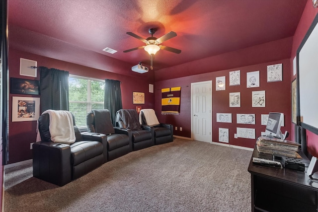 carpeted home theater with a textured ceiling and ceiling fan