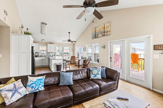 living room featuring light wood-type flooring, ceiling fan, and high vaulted ceiling