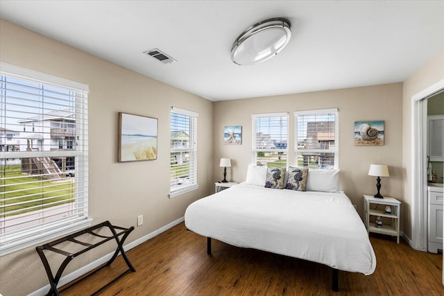 bedroom featuring multiple windows and dark hardwood / wood-style flooring