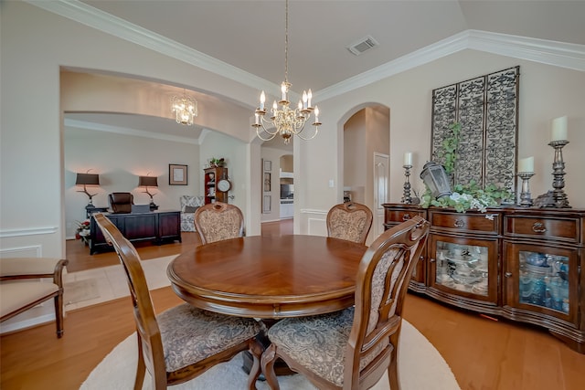 dining space with a chandelier, light wood-type flooring, vaulted ceiling, and ornamental molding