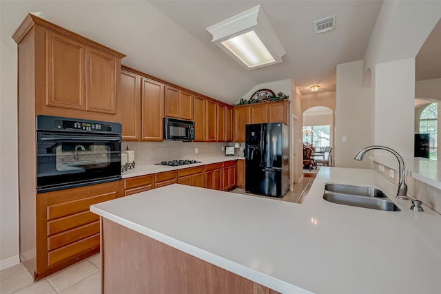 kitchen featuring decorative backsplash, vaulted ceiling, sink, black appliances, and light tile patterned floors