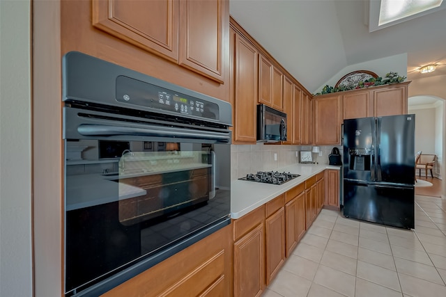 kitchen with light tile patterned flooring, backsplash, lofted ceiling, and black appliances