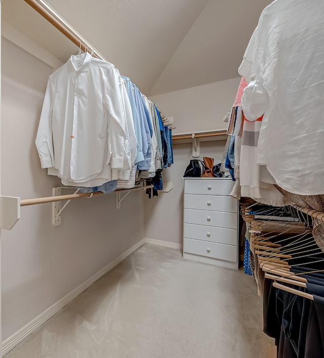 walk in closet with light colored carpet and lofted ceiling