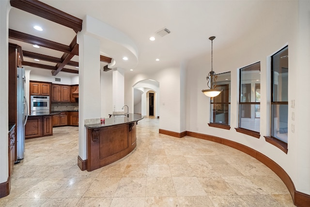 kitchen featuring beamed ceiling, tasteful backsplash, stainless steel appliances, decorative light fixtures, and dark stone countertops