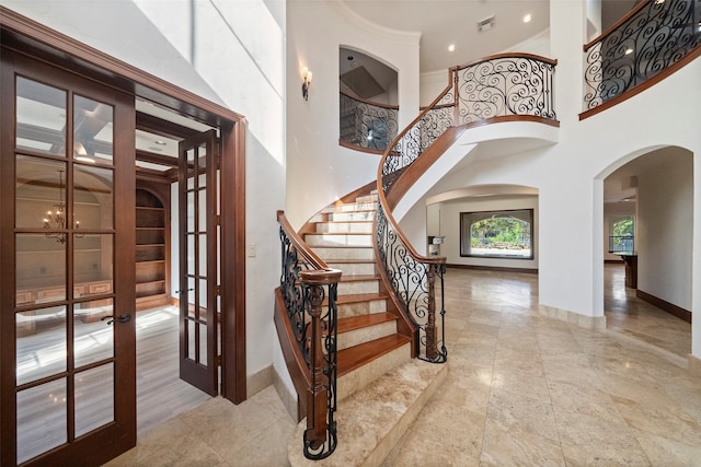 foyer entrance with french doors, a chandelier, and a high ceiling