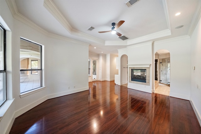 unfurnished living room featuring ornamental molding, a multi sided fireplace, a raised ceiling, and dark hardwood / wood-style flooring