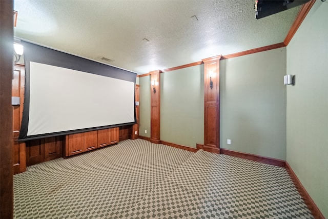 carpeted cinema room featuring ornamental molding, a textured ceiling, and ornate columns