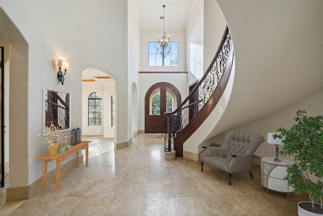 entrance foyer with ornamental molding, a high ceiling, and a notable chandelier