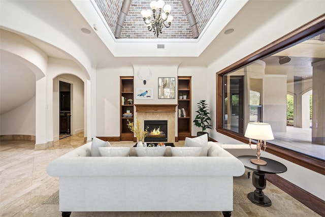 living room featuring a high end fireplace, a skylight, a chandelier, and built in features