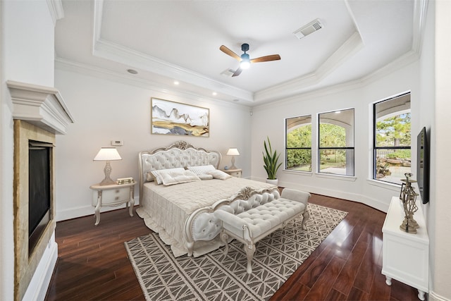 bedroom with crown molding, a tray ceiling, dark hardwood / wood-style flooring, and ceiling fan