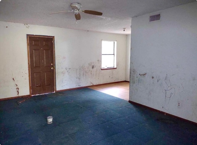 unfurnished room with ceiling fan and a textured ceiling