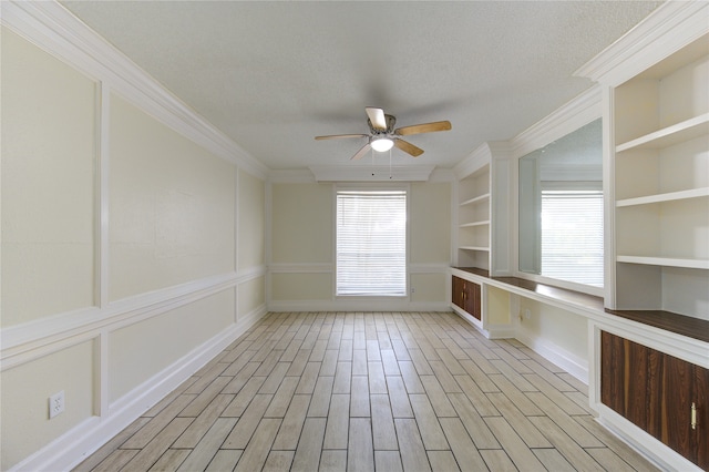 spare room featuring ceiling fan, a textured ceiling, light hardwood / wood-style flooring, ornamental molding, and built in features