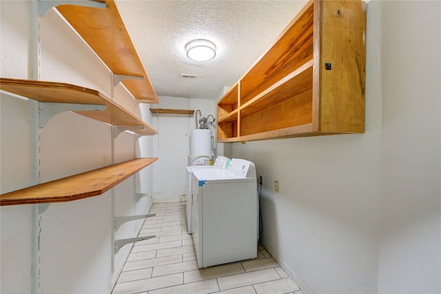 washroom with water heater, a textured ceiling, and separate washer and dryer