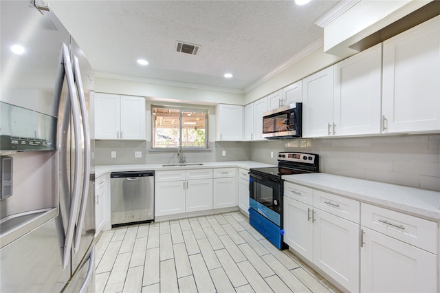 kitchen featuring white cabinets, stainless steel appliances, sink, and a textured ceiling