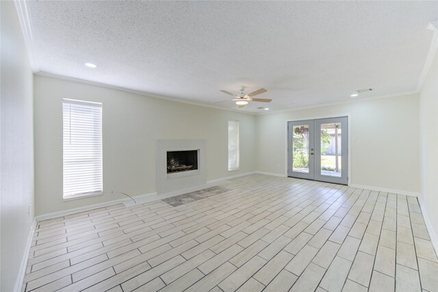 unfurnished living room with french doors, a textured ceiling, ceiling fan, light hardwood / wood-style floors, and crown molding