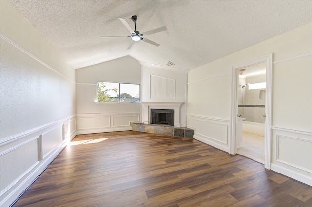 unfurnished living room featuring a textured ceiling, vaulted ceiling, a fireplace, and dark hardwood / wood-style floors