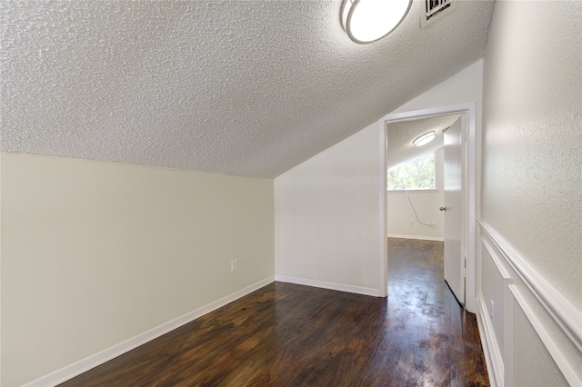 bonus room with a textured ceiling, vaulted ceiling, and dark hardwood / wood-style floors