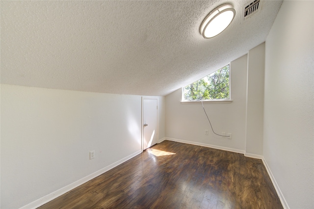 additional living space with a textured ceiling, lofted ceiling, and dark hardwood / wood-style flooring