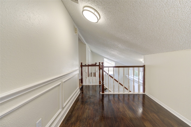 hall featuring lofted ceiling, a textured ceiling, and dark hardwood / wood-style floors