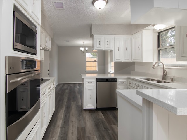 kitchen with white cabinetry, appliances with stainless steel finishes, dark hardwood / wood-style flooring, and kitchen peninsula