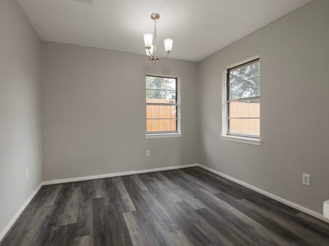 empty room with dark wood-type flooring, a textured ceiling, and plenty of natural light