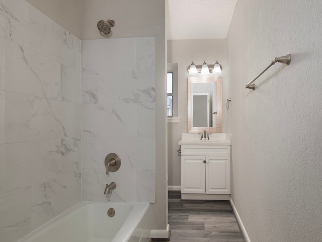 bathroom featuring vanity, hardwood / wood-style flooring, tiled shower / bath combo, and a textured ceiling