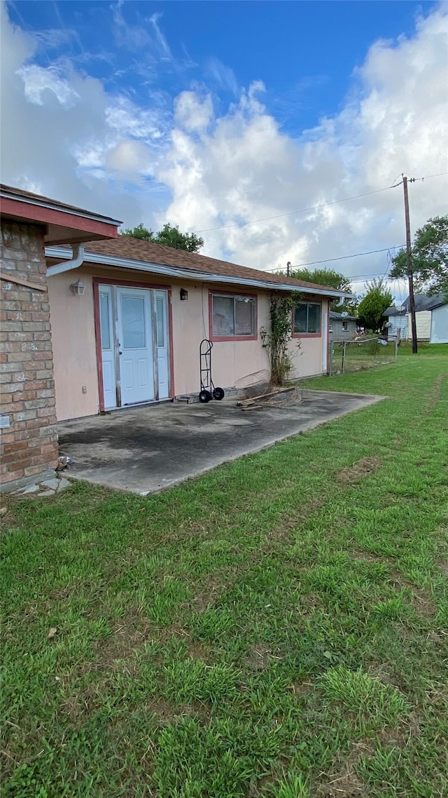 rear view of property with a lawn and a patio