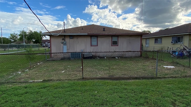 rear view of property with cooling unit and a yard