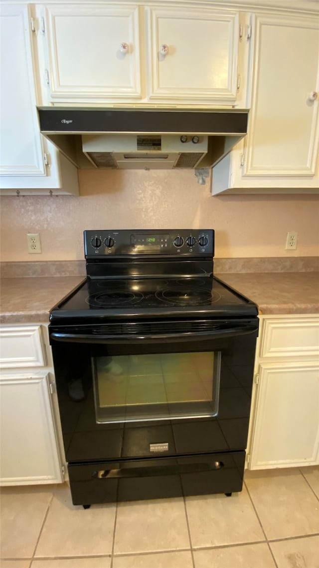 kitchen with black range with electric stovetop, light tile patterned floors, and white cabinetry