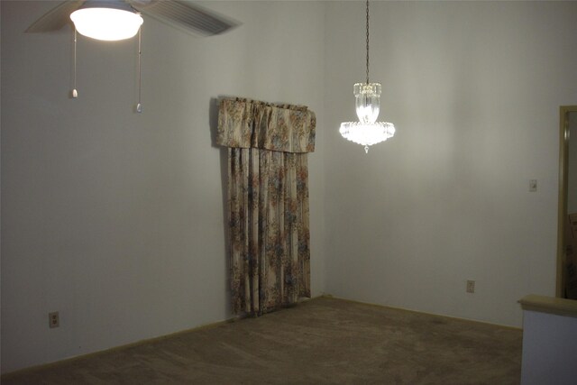 unfurnished dining area featuring ceiling fan with notable chandelier and carpet