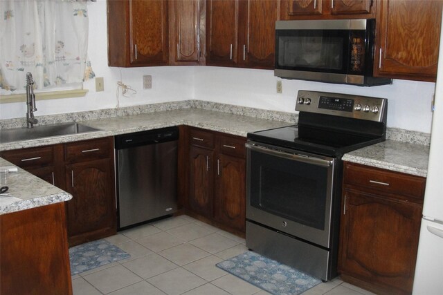 kitchen with light tile patterned floors, appliances with stainless steel finishes, light countertops, and a sink