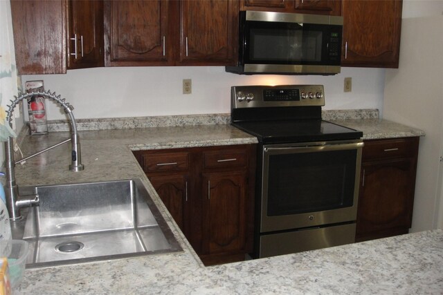 kitchen with dark brown cabinets, appliances with stainless steel finishes, and a sink