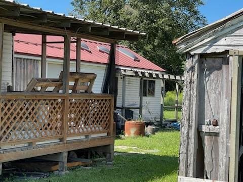 rear view of house with a lawn, a storage shed, and a deck