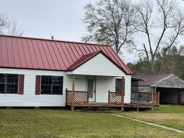 back of property with covered porch and a yard